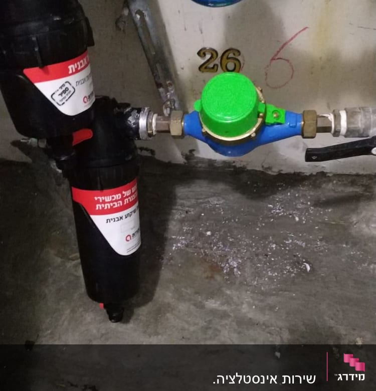 מד מים עם מכסה ירוק וצינורות מחוברים